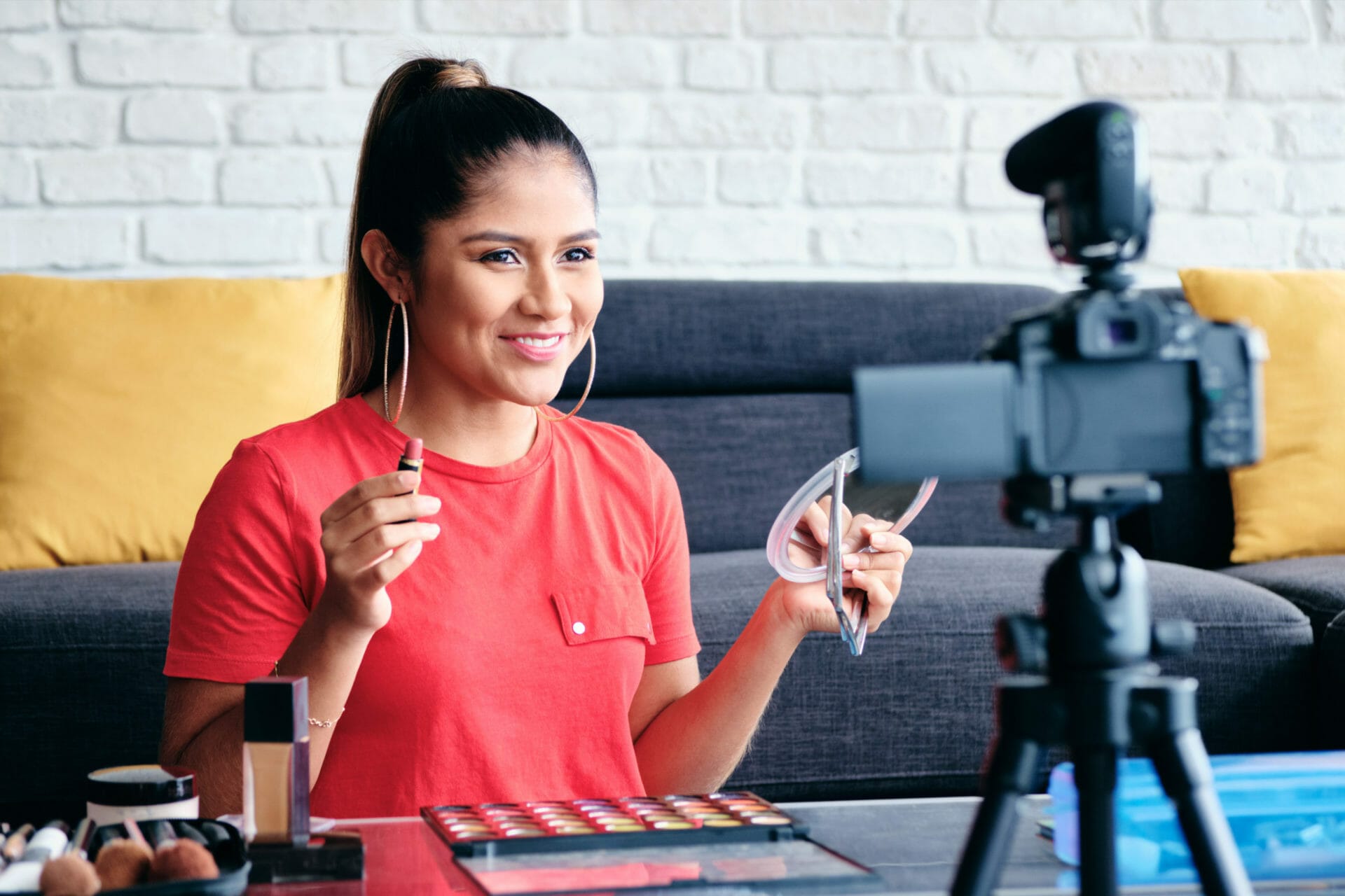 Happy girl at home speaking about make up in front of camera. Video blogger recording message for social media and internet marketing west pam beach