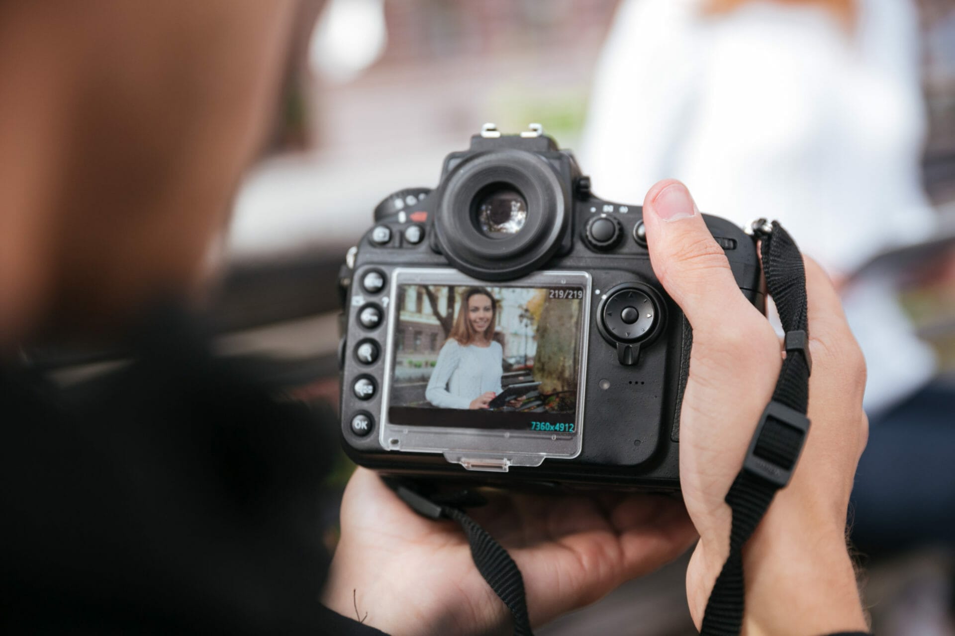 Professional photo camera holded by man photographer who taking photos of beautiful young woman in park marketing west pam beach
